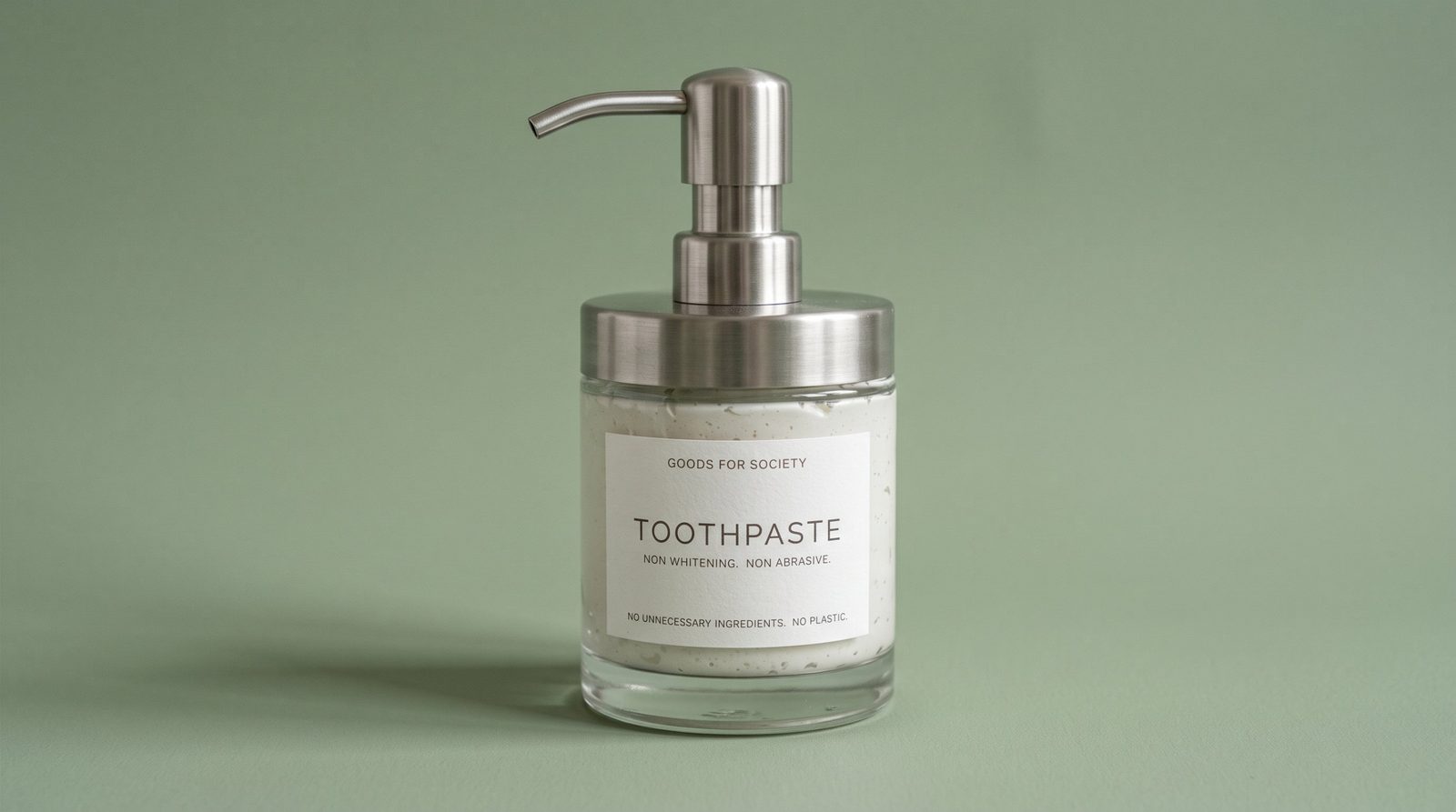 Goods For Society Toothpaste in a clear glass jar with a stainless steel pump